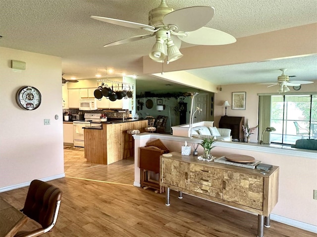 living room with a textured ceiling, light wood-style flooring, and a ceiling fan