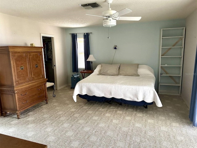 bedroom featuring a textured ceiling, a ceiling fan, visible vents, and light colored carpet