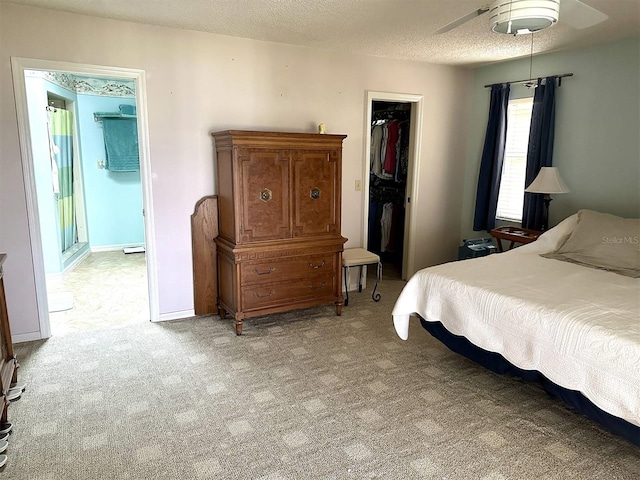 bedroom with a textured ceiling, light carpet, baseboards, a spacious closet, and a closet