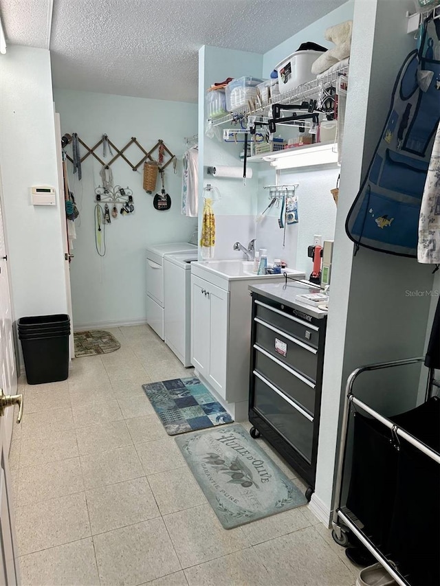 interior space featuring cabinet space, baseboards, washing machine and clothes dryer, a textured ceiling, and a sink