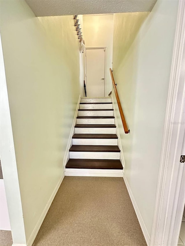 staircase featuring carpet floors and baseboards