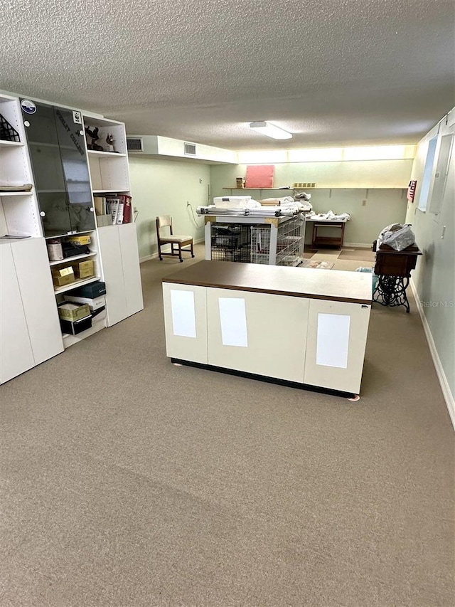 kitchen featuring carpet floors, visible vents, a textured ceiling, and baseboards