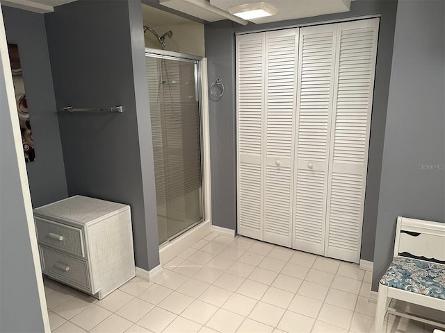 full bathroom with a stall shower, a closet, and tile patterned floors