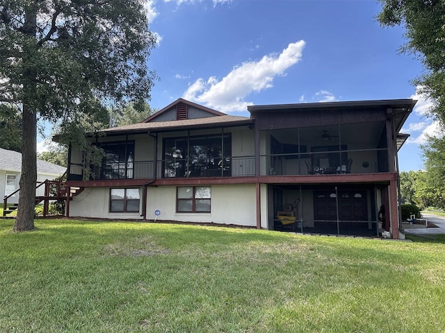 back of property with a sunroom, stucco siding, and a yard