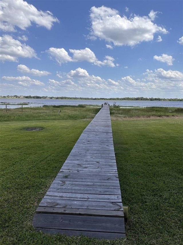 dock area with a lawn and a water view