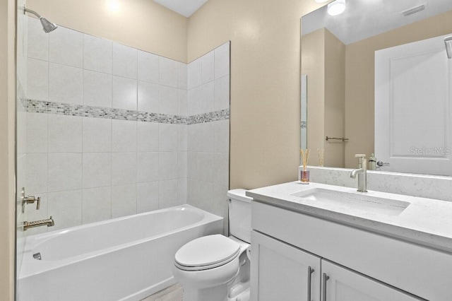 full bathroom with tiled shower / bath, vanity, and toilet