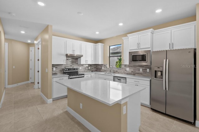 kitchen featuring stainless steel appliances, backsplash, a center island, and white cabinetry