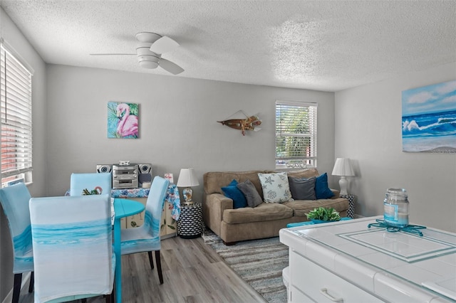 living room featuring ceiling fan, light hardwood / wood-style floors, and a textured ceiling