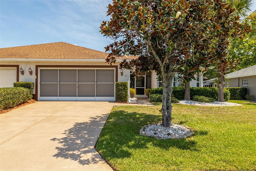 view of front of home featuring a garage, driveway, a front yard, and stucco siding