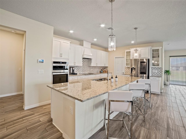 kitchen with a large island with sink, white cabinetry, and sink