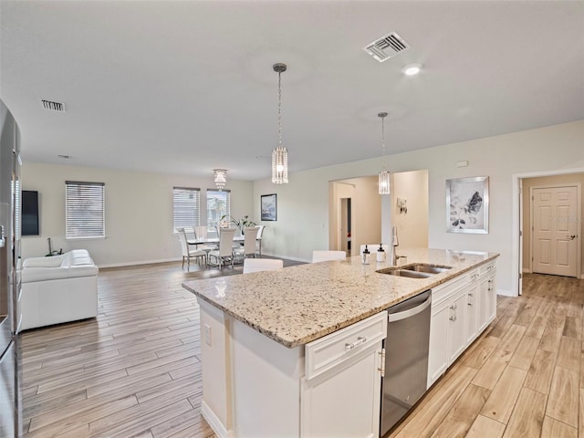 kitchen featuring sink, white cabinetry, dishwasher, hanging light fixtures, and a kitchen island with sink