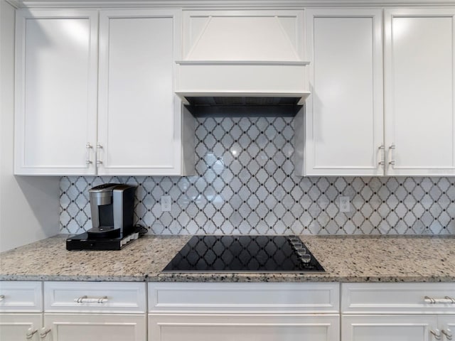 kitchen with black electric cooktop, white cabinetry, custom exhaust hood, and decorative backsplash