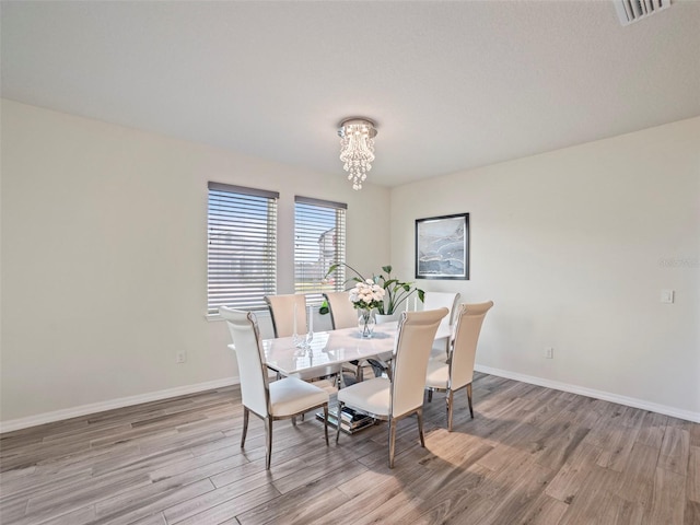 dining room with light wood-type flooring and a notable chandelier