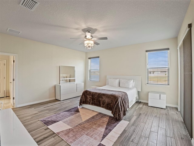 bedroom featuring light wood-type flooring, ceiling fan, and a textured ceiling