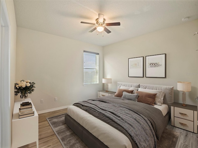 bedroom featuring ceiling fan, hardwood / wood-style floors, and a textured ceiling