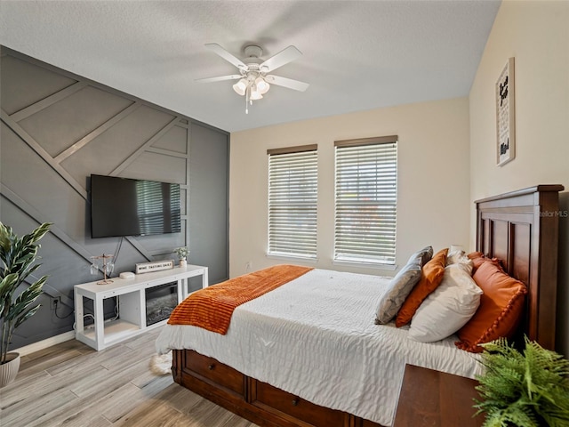 bedroom featuring ceiling fan, light wood-type flooring, and a textured ceiling