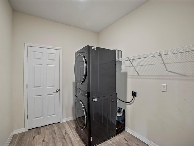 clothes washing area featuring light hardwood / wood-style floors and stacked washer / dryer