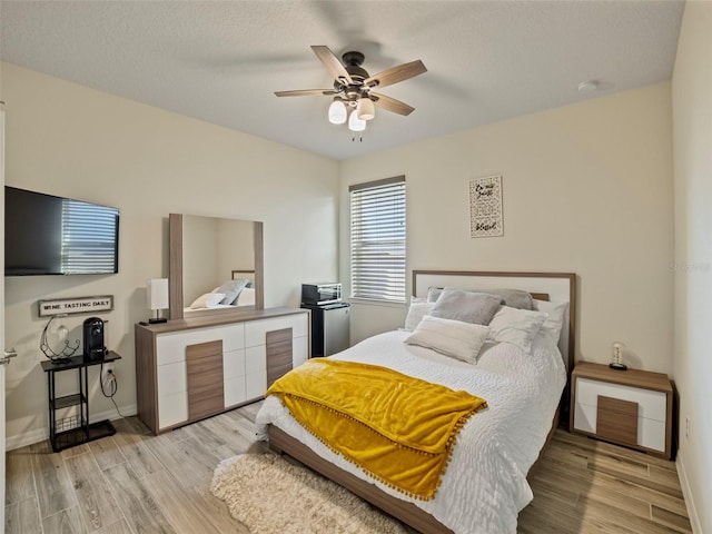 bedroom with a ceiling fan, baseboards, and light wood-style floors