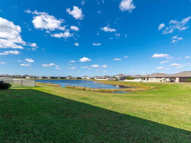 view of yard with a residential view, fence, and a water view