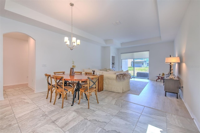 dining space with a tray ceiling and a chandelier