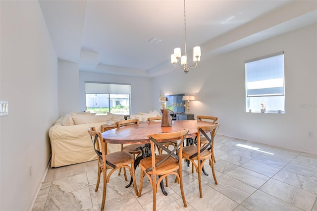 dining area with a raised ceiling and a chandelier