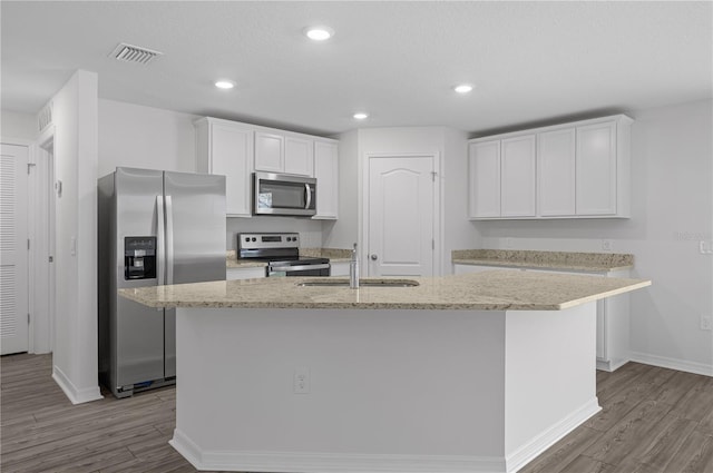 kitchen featuring a center island with sink, sink, white cabinets, light wood-type flooring, and appliances with stainless steel finishes