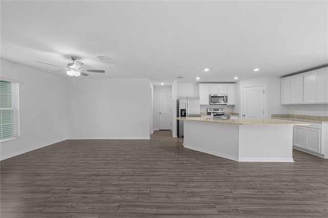 kitchen with dark wood-type flooring, appliances with stainless steel finishes, an island with sink, and white cabinets