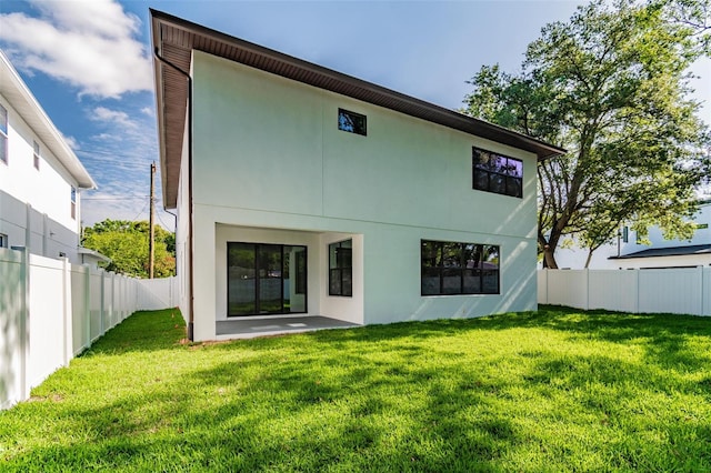 back of house featuring stucco siding, a fenced backyard, and a yard