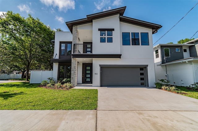 contemporary house featuring a balcony, driveway, a front lawn, and stucco siding