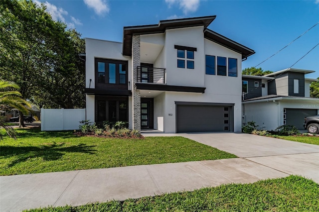 modern home with driveway, fence, a balcony, and stucco siding