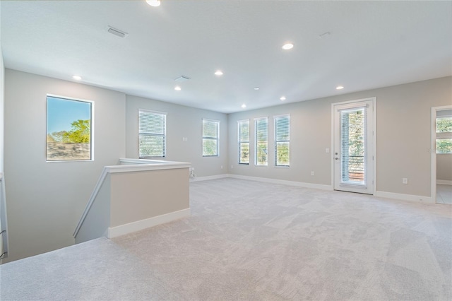 unfurnished room with light carpet, visible vents, baseboards, and recessed lighting