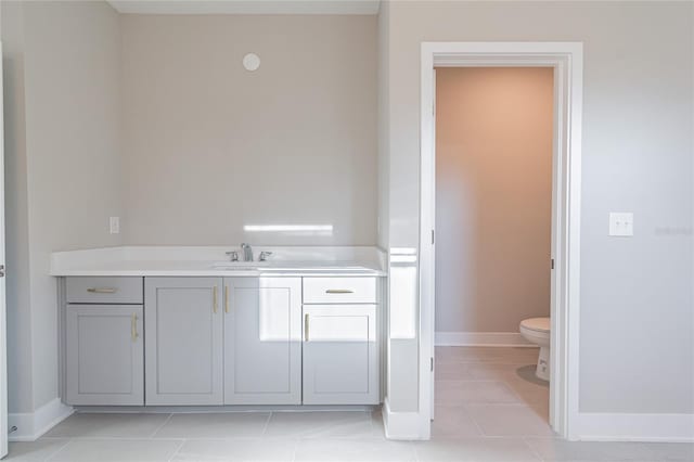 bathroom with tile patterned flooring, baseboards, vanity, and toilet