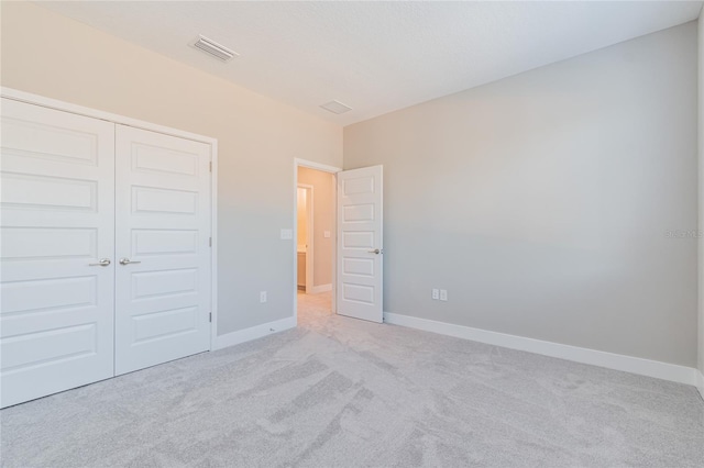 unfurnished bedroom featuring a closet, light colored carpet, visible vents, and baseboards