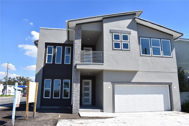 contemporary house featuring an attached garage, a balcony, and stucco siding