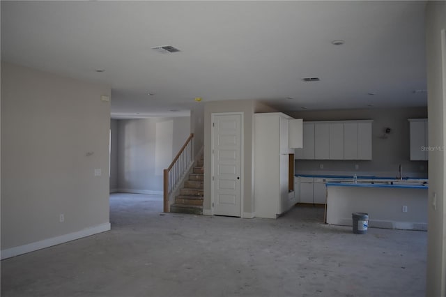 kitchen with concrete flooring, visible vents, baseboards, and white cabinetry