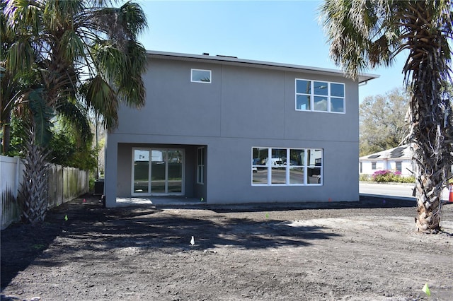 rear view of house with fence and stucco siding