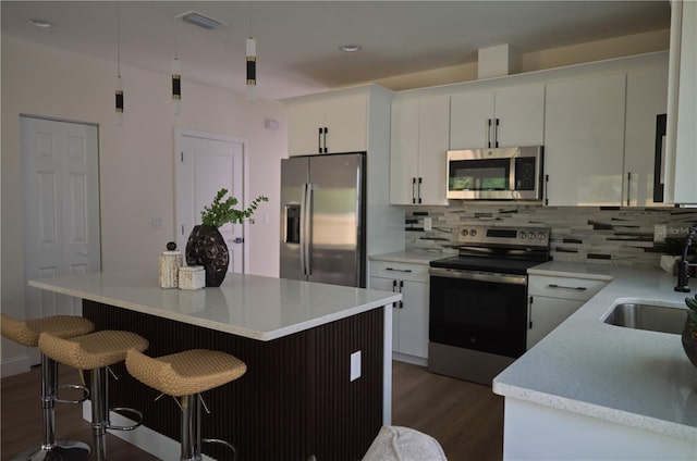 kitchen with white cabinets, a center island, decorative backsplash, and appliances with stainless steel finishes