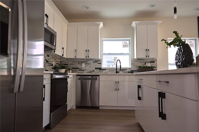 kitchen featuring appliances with stainless steel finishes, white cabinetry, decorative backsplash, sink, and dark hardwood / wood-style floors