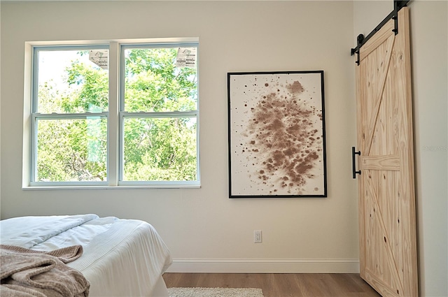 bedroom featuring hardwood / wood-style floors, multiple windows, and a barn door