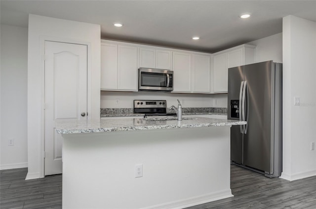 kitchen with a center island with sink, dark wood-type flooring, appliances with stainless steel finishes, and white cabinetry