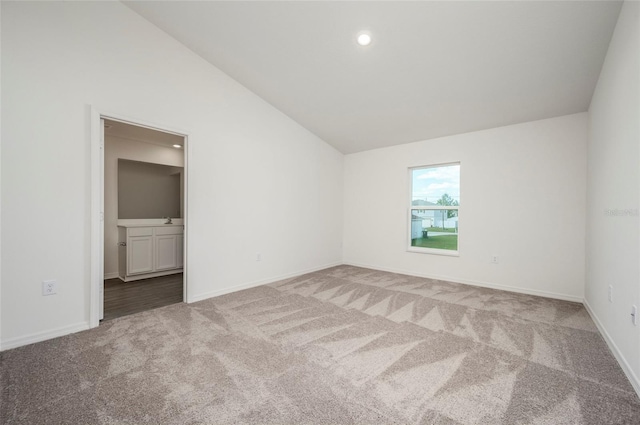 empty room with vaulted ceiling and light colored carpet