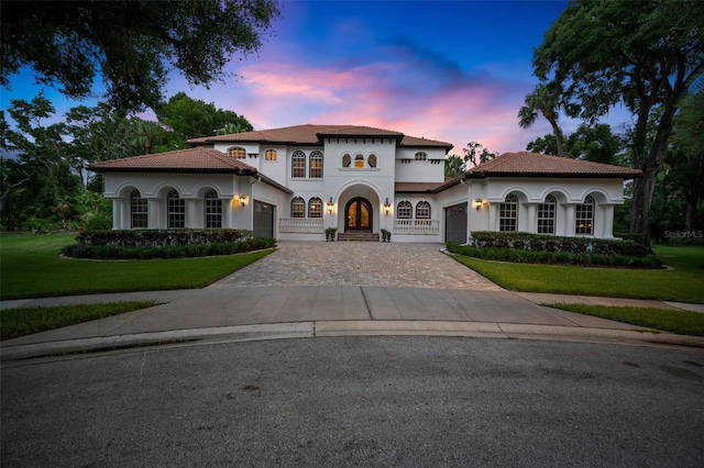 mediterranean / spanish house with french doors, a balcony, and a yard