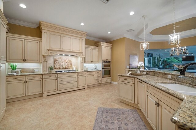 kitchen with pendant lighting, cream cabinetry, light stone counters, and sink