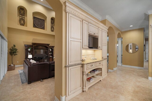 kitchen featuring light carpet, light stone countertops, cream cabinetry, and crown molding