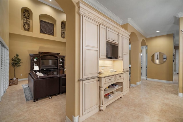 kitchen featuring light stone counters, ornamental molding, cream cabinets, and backsplash