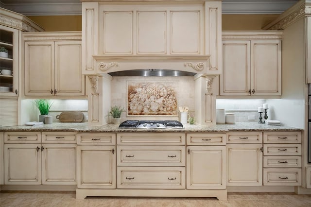 kitchen with light stone countertops, cream cabinetry, stainless steel gas cooktop, and backsplash