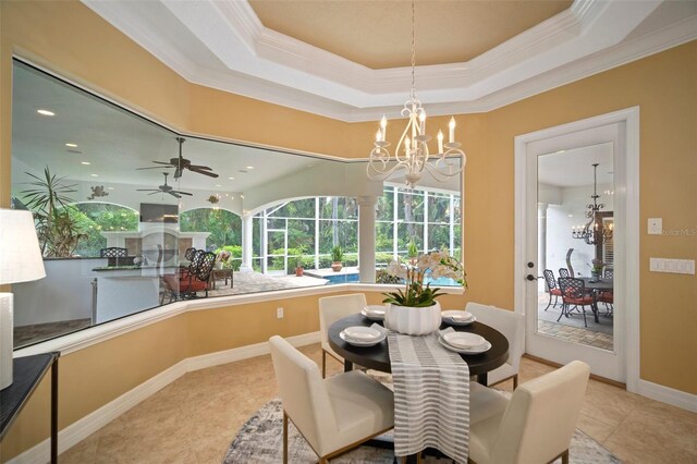 dining space with tile floors, ornamental molding, ceiling fan with notable chandelier, and a raised ceiling