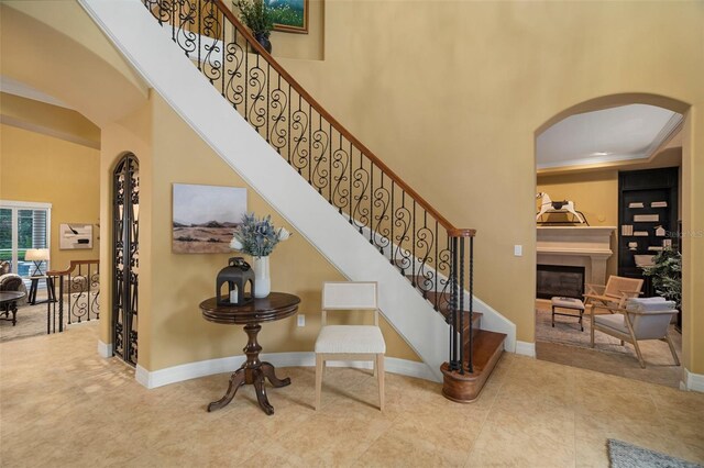 staircase with tile flooring, a high ceiling, and crown molding