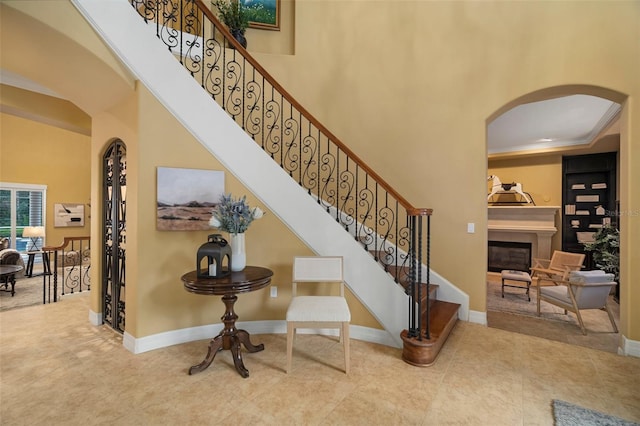 stairway featuring a high ceiling, ornamental molding, and tile patterned flooring