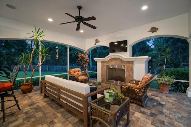 view of patio / terrace with ceiling fan and an outdoor living space with a fireplace